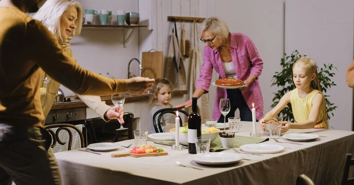 Una cálida reunión familiar en interiores con miembros de múltiples generaciones disfrutando de la preparación de la cena.