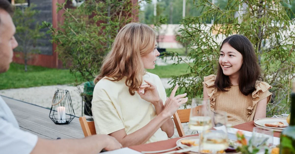 Familia reunida al aire libre para una animada conversación durante la cena en un día cálido.