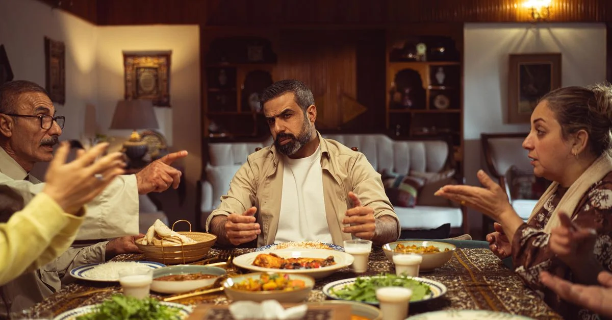 Una reunión familiar durante la cena, con una animada conversación en un ambiente interior, donde se puede degustar la gastronomía de Oriente Medio.