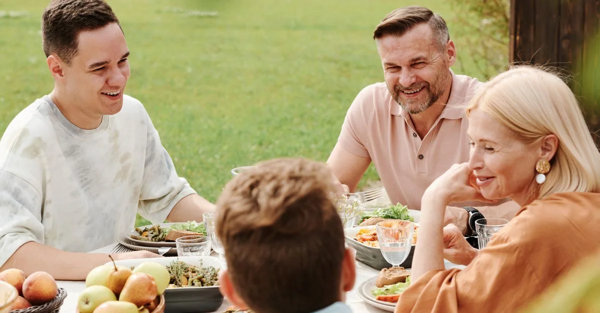 Una familia alegre disfrutando de una comida al aire libre, compartiendo risas y calidez.