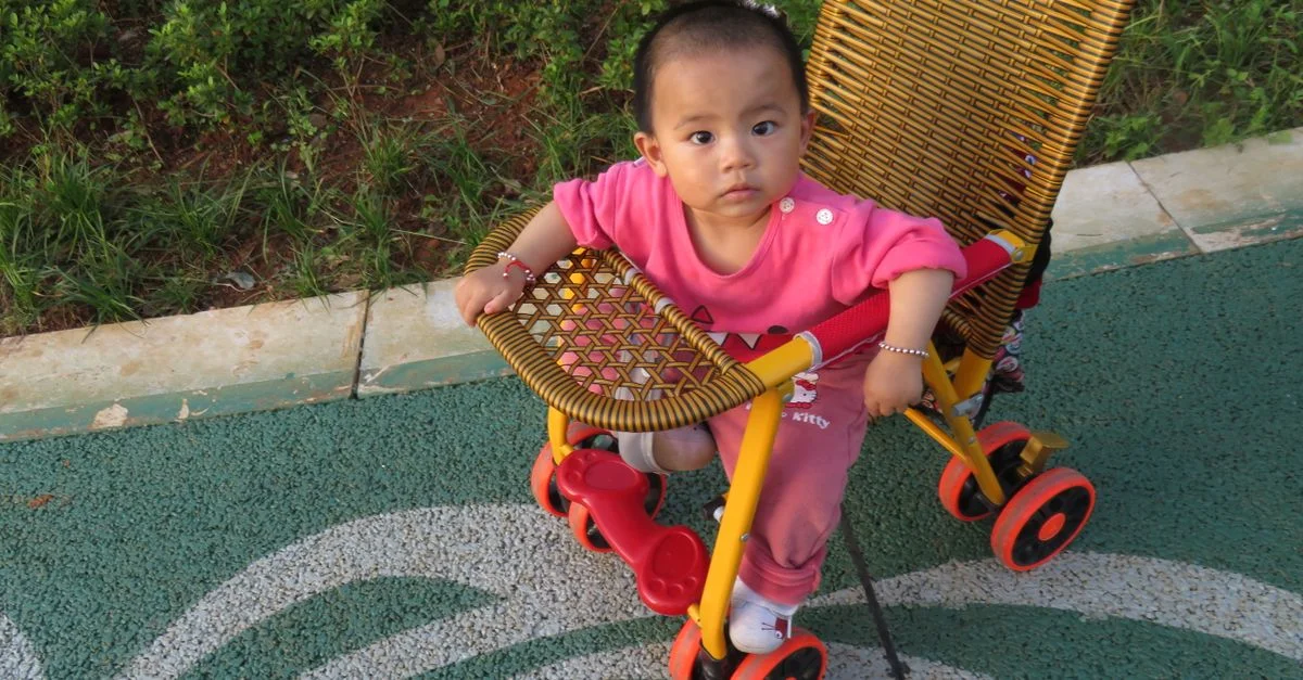 Bébé adorable dans une poussette tissée profitant d'une journée ensoleillée à l'extérieur. Parfait pour les thèmes de l'enfance et de l'innocence.