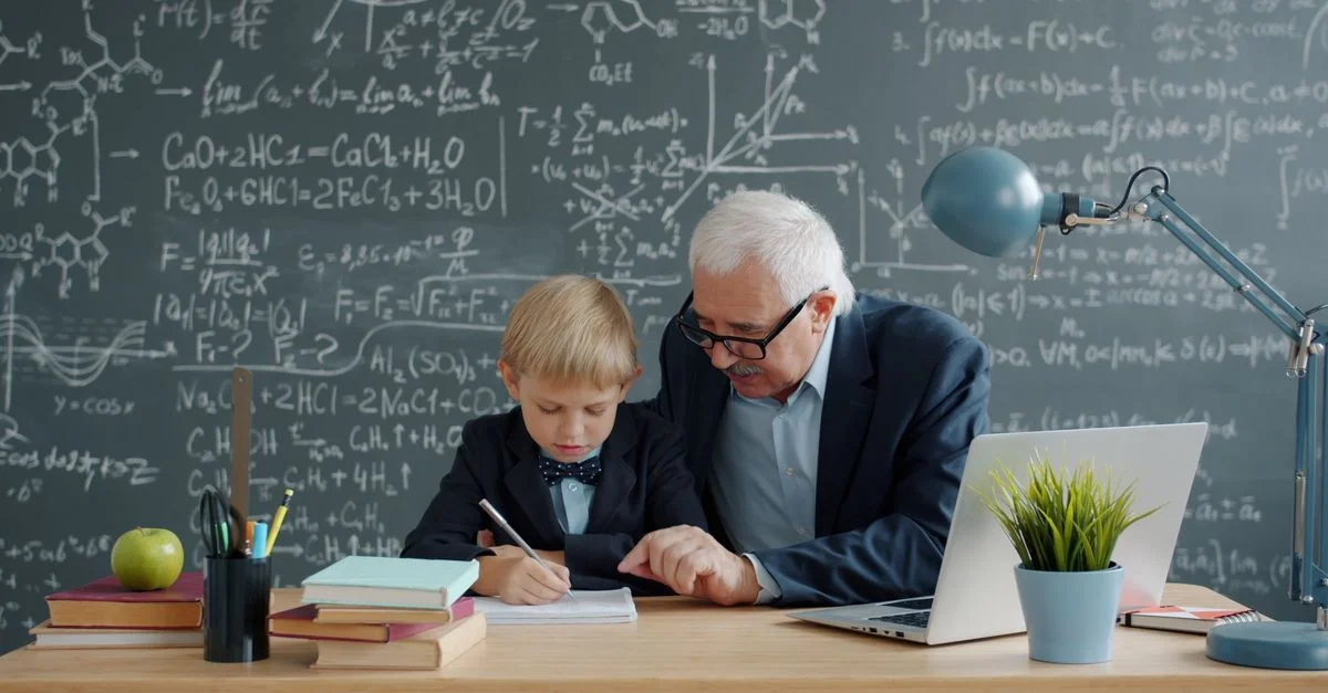 Un homme âgé enseigne les mathématiques à un jeune garçon sur un tableau noir.