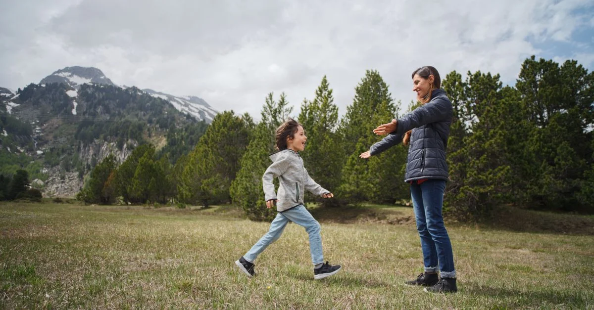 Un momento alegre entre madre e hijo en las montañas, rodeados de vegetación.