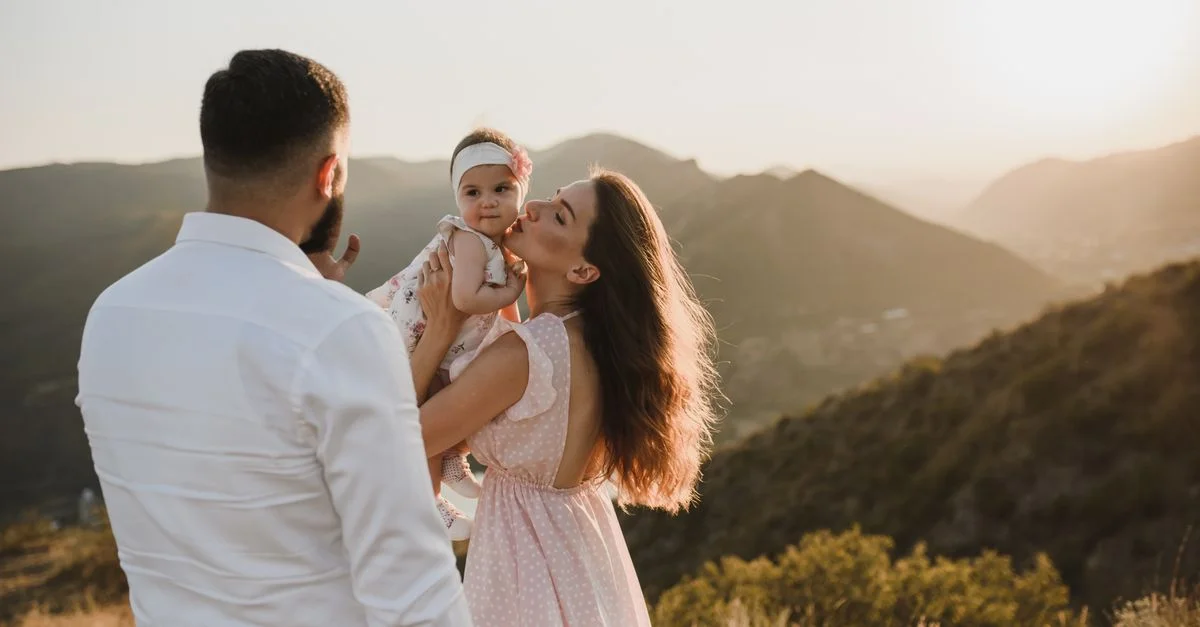 Una familia amorosa disfrutando de una vista pintoresca del atardecer desde la cima de una montaña en verano.