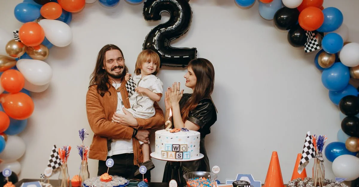 Una familia celebra el segundo cumpleaños de un niño con globos y pastel en el interior.