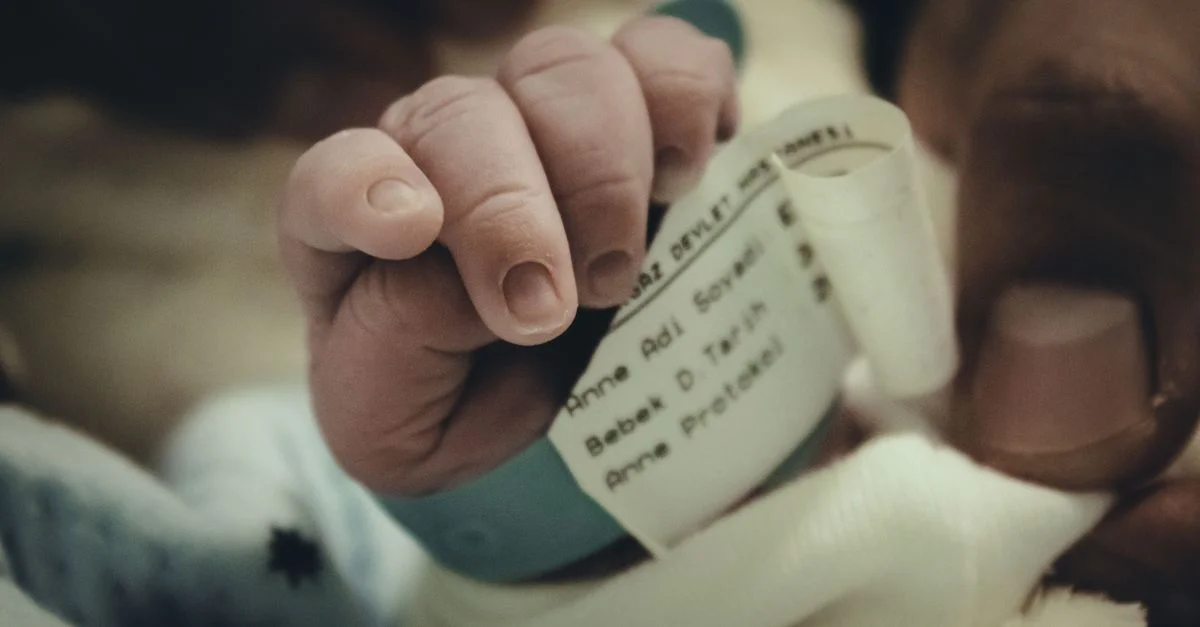 Close-up de la mano de un bebé recién nacido con una pulsera de hospital, simbolizando nueva vida y cuidado.