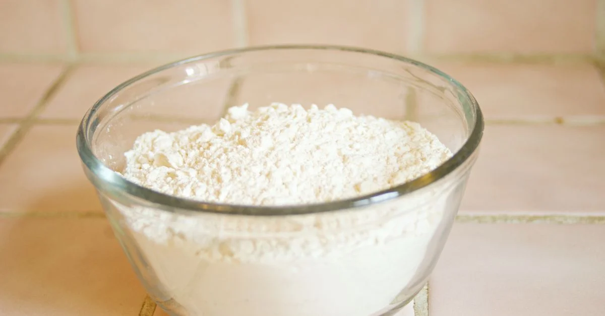 Primer plano de un cuenco de vidrio lleno de harina blanca, un ingrediente común en la repostería.