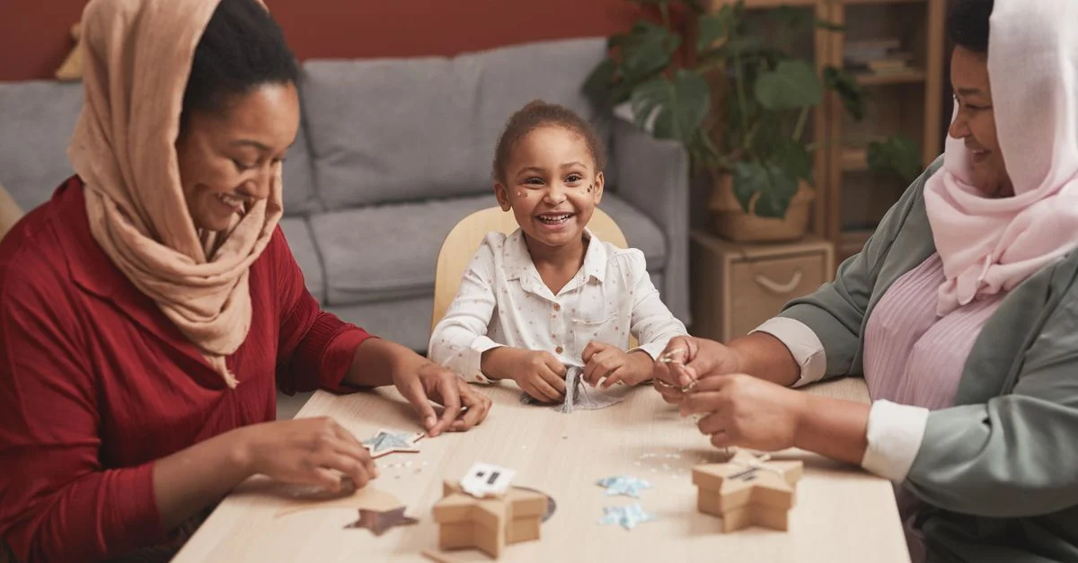 Tres generaciones disfrutando de una sesión creativa de manualidades en casa, llena de sonrisas y alegría familiar.