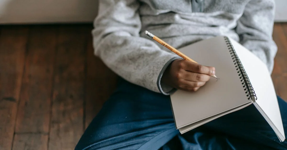 Primer plano de un niño escribiendo en un cuaderno, centrándose en la educación y la creatividad.