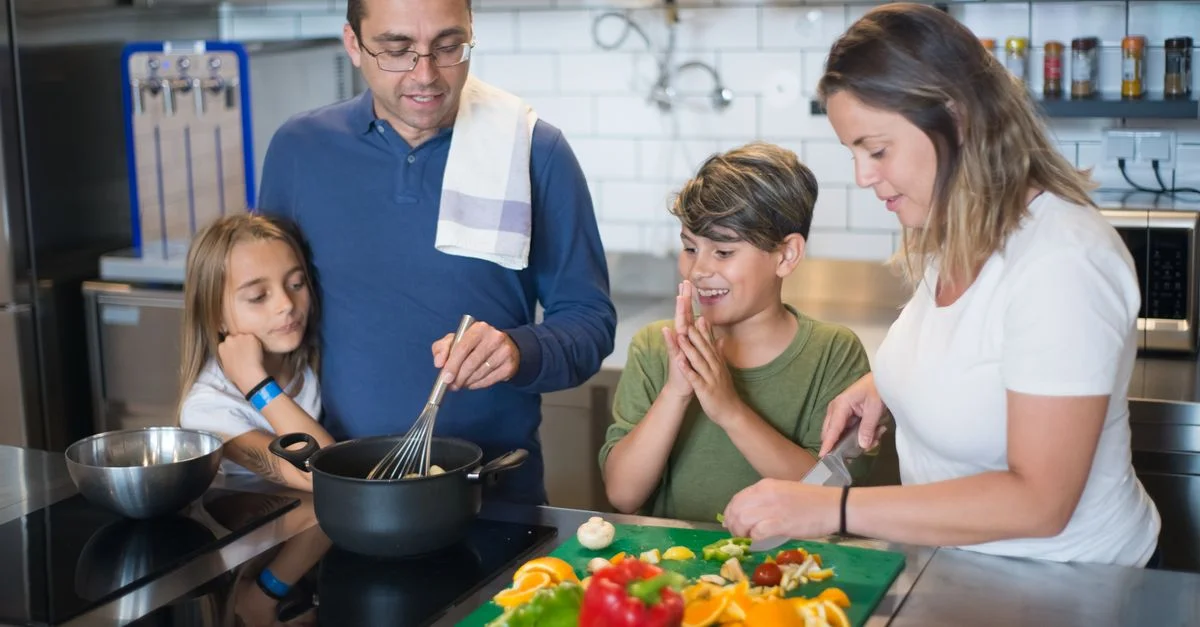Una familia feliz colabora en la preparación de una comida en una cocina elegante.