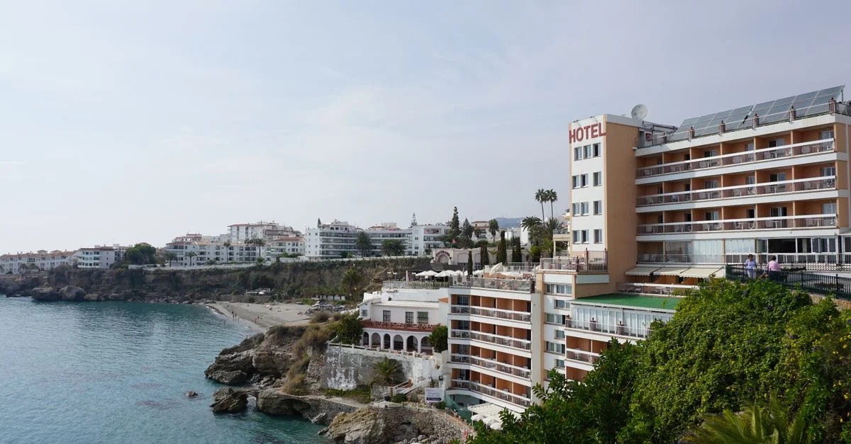 Hotel elegante en la costa rocosa con vista a la playa y al océano.