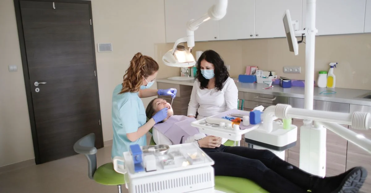 Dentista mujer realiza tratamiento a un paciente en una clínica dental moderna.