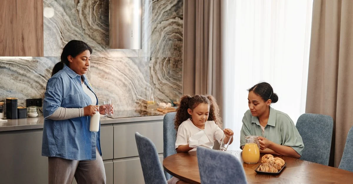 Una familia disfruta del desayuno con pasteles y bebidas en un ambiente de cocina moderna.