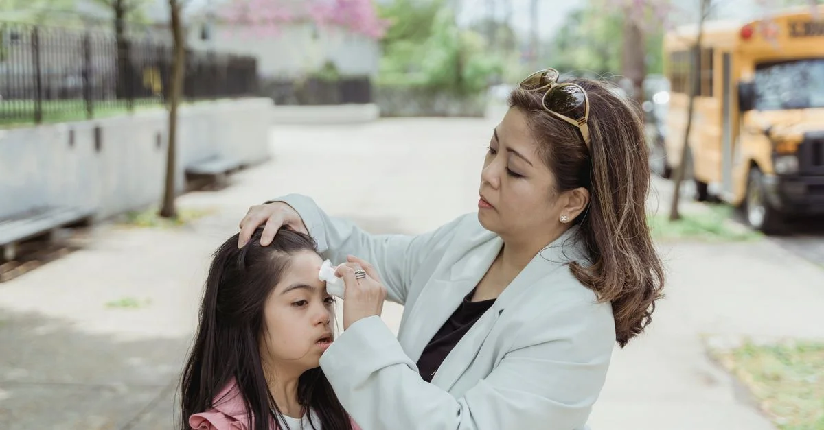Una madre limpia suavemente la cara de su hija mientras están al aire libre en primavera.