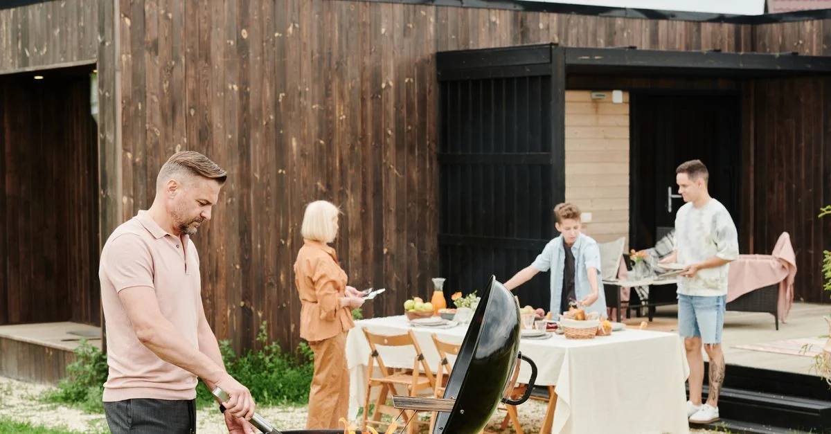 Familia disfrutando de una barbacoa con comida y conversación al aire libre.
