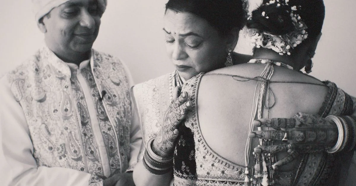 Un momento conmovedor en el que la familia se abraza en una boda tradicional india, destacando la vestimenta cultural y la emoción.