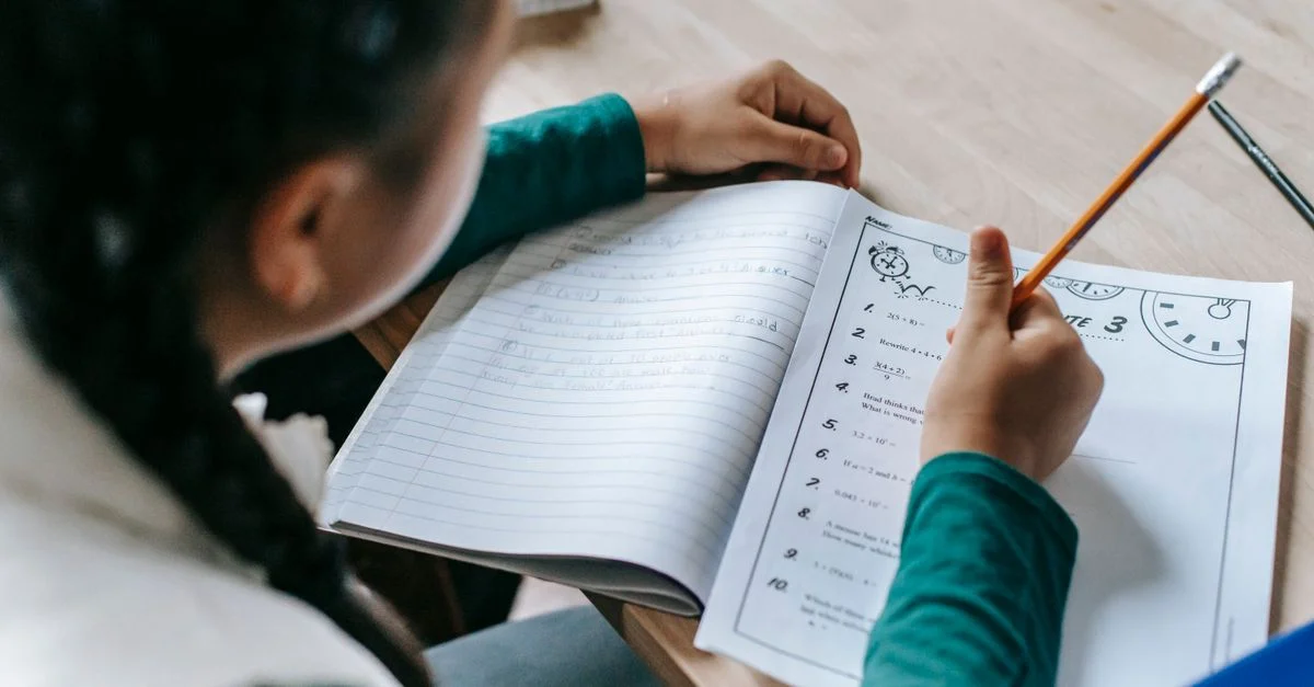 Niña escribiendo atentamente en un cuaderno para los deberes. Perfecto para contenido educativo.