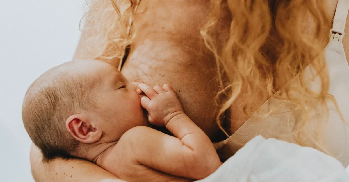 Imagen en primer plano de una madre amamantando amorosamente a su recién nacido, destacando el vínculo y la conexión materna.