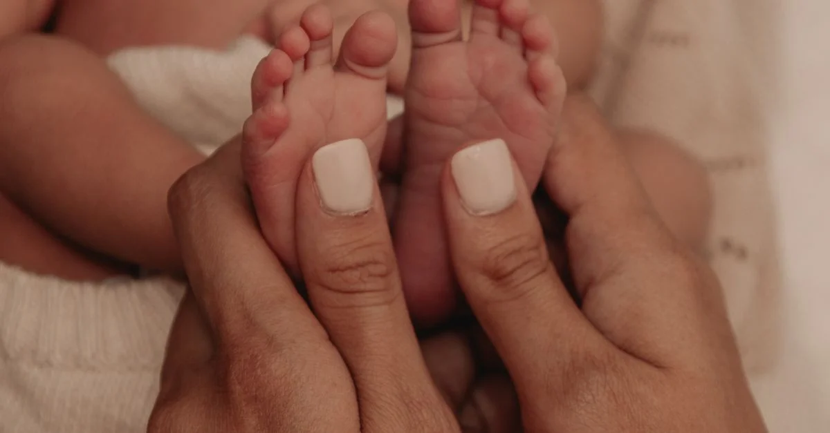 Tierno primer plano de una madre sosteniendo suavemente los pies de su recién nacido, simbolizando amor y cuidado.