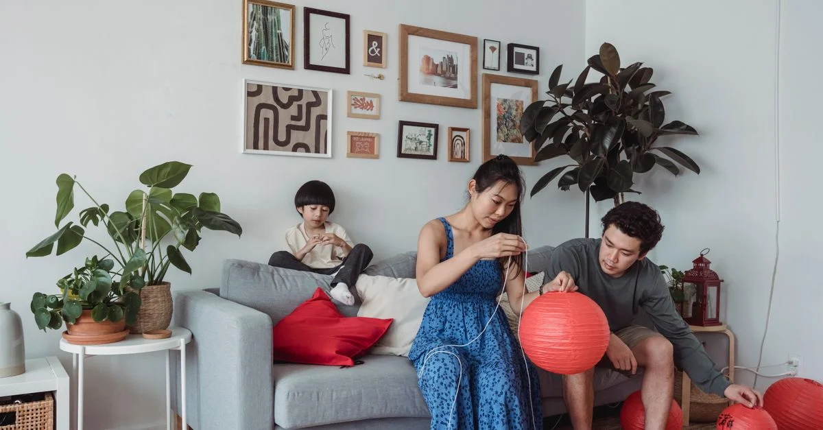 Familia decorando su sala de estar con faroles chinos rojos para una celebración festiva.