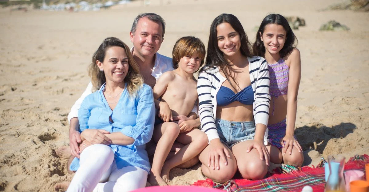 Familia sonriente disfrutando de un día soleado en la playa en Portugal.