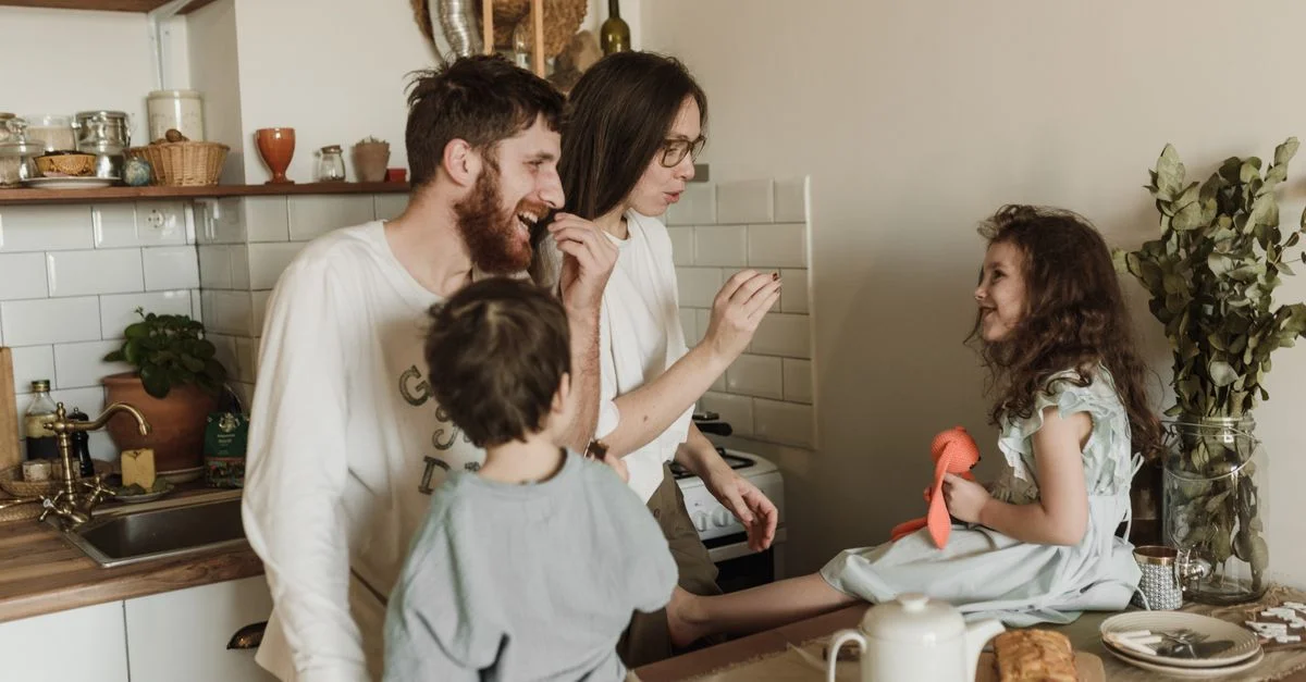 Una familia alegre comparte un momento de risa en una cocina acogedora, capturando amor y unidad.