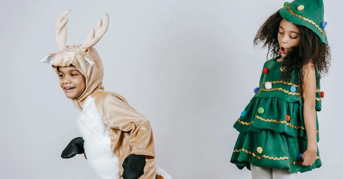Dos adorables niños con disfraces temáticos de Navidad, trayendo alegría festiva al interior.