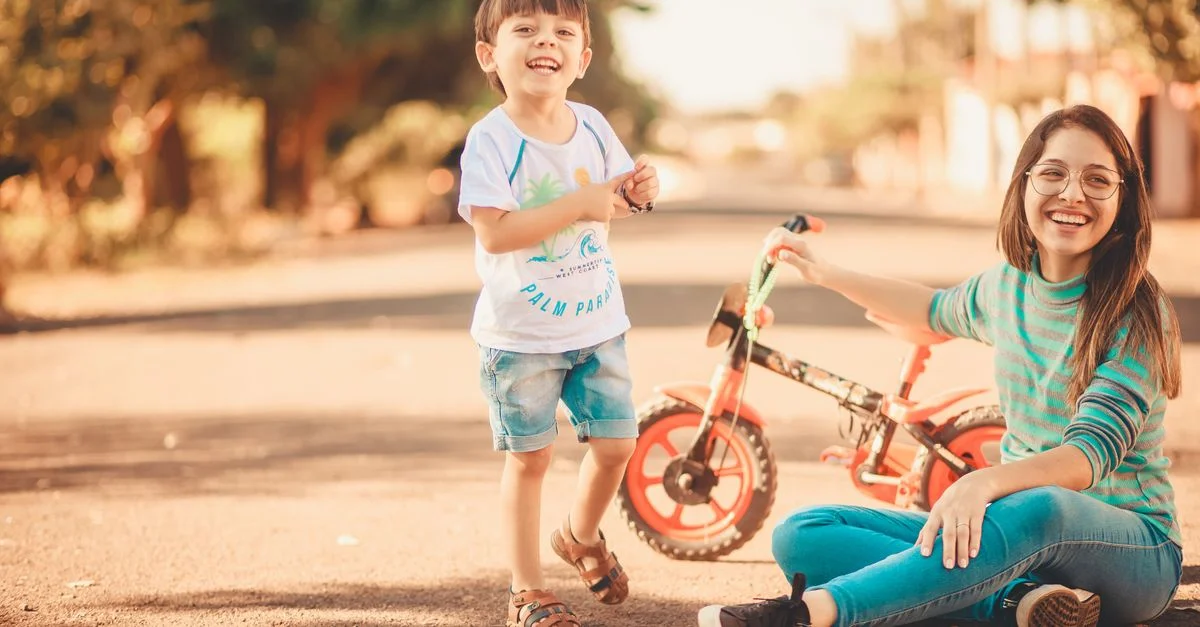 Un momento alegre de una madre y un hijo compartiendo al aire libre, disfrutando de un día soleado con un triciclo.