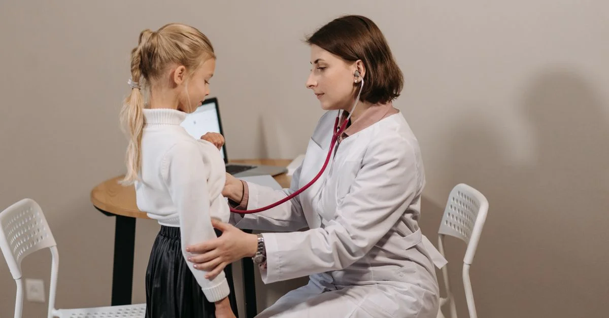 Un pediatra escucha el corazón de un niño durante un chequeo en un entorno clínico.