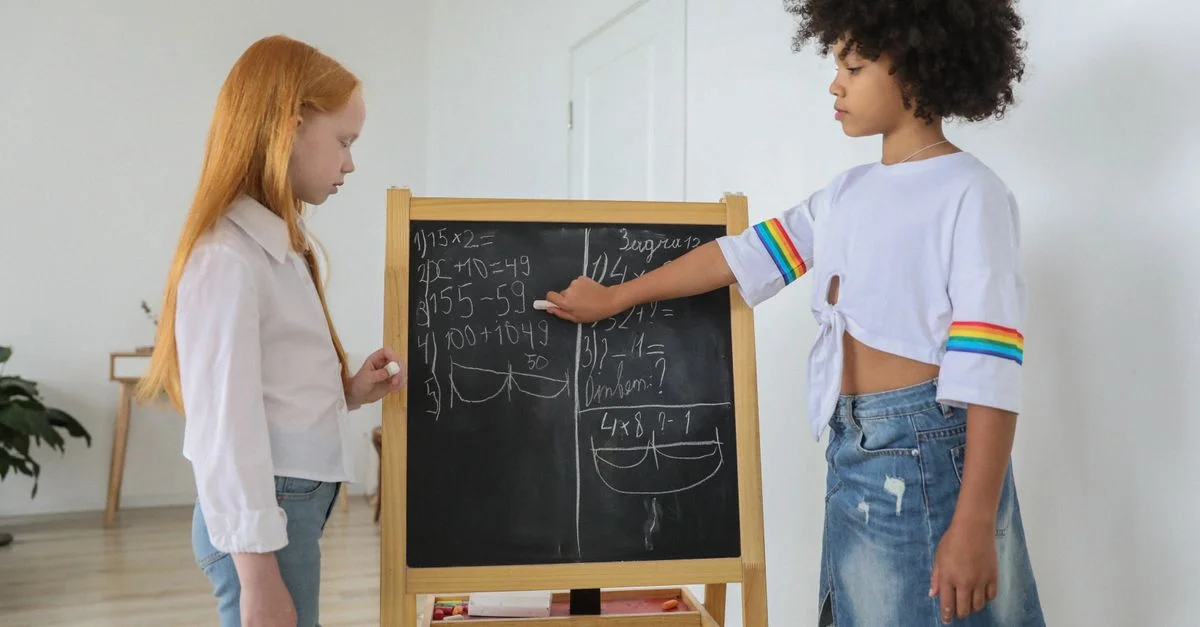 Dos chicas resolviendo ecuaciones matemáticas en una pizarra en un aula brillante.