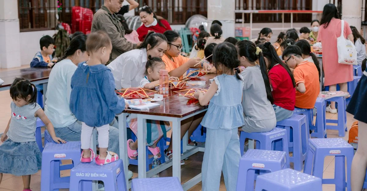 Niños y adultos participan en una actividad artística grupal creativa en interiores, fomentando el trabajo en equipo y la creatividad.