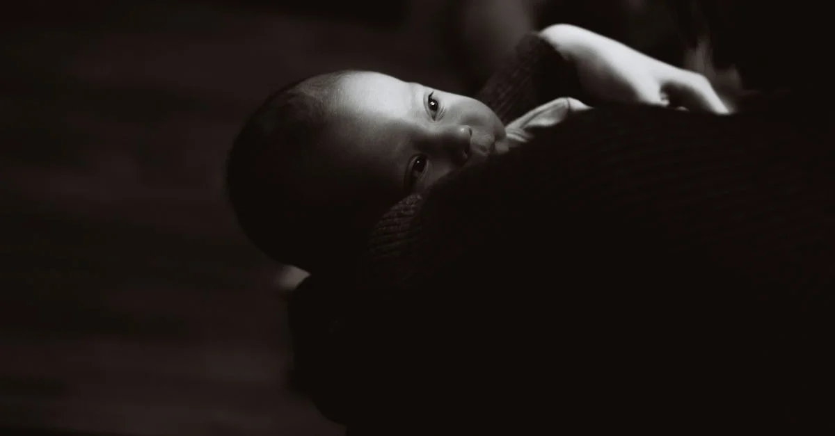 Captura emotiva en blanco y negro de un bebé acunado en un abrazo cariñoso, destacando la inocencia.